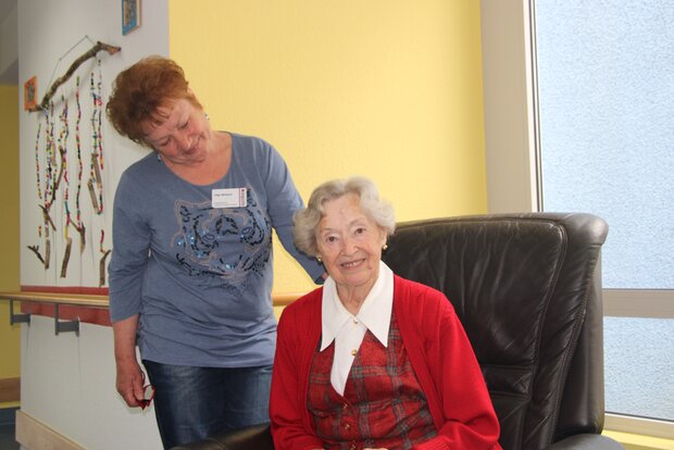 Bild zeigt lächelnde Seniorin auf Sessel