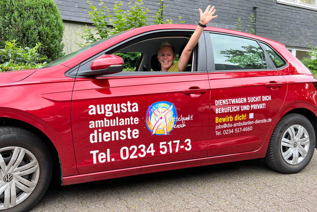 Rotes Auto der Augusta Pflege zeigt eine freundliche Mitarbeiterin