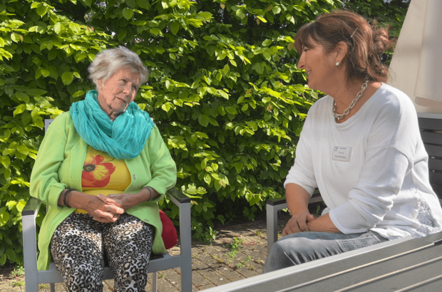 Bild zeigt Mitarbeiterin unterhält sich mit einem Gast in der Tagespflege Hattingen