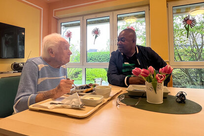 Bild zeigt Mitarbeiter unterhält sich mit Gast beim Essen in der Kurzzeitpflege